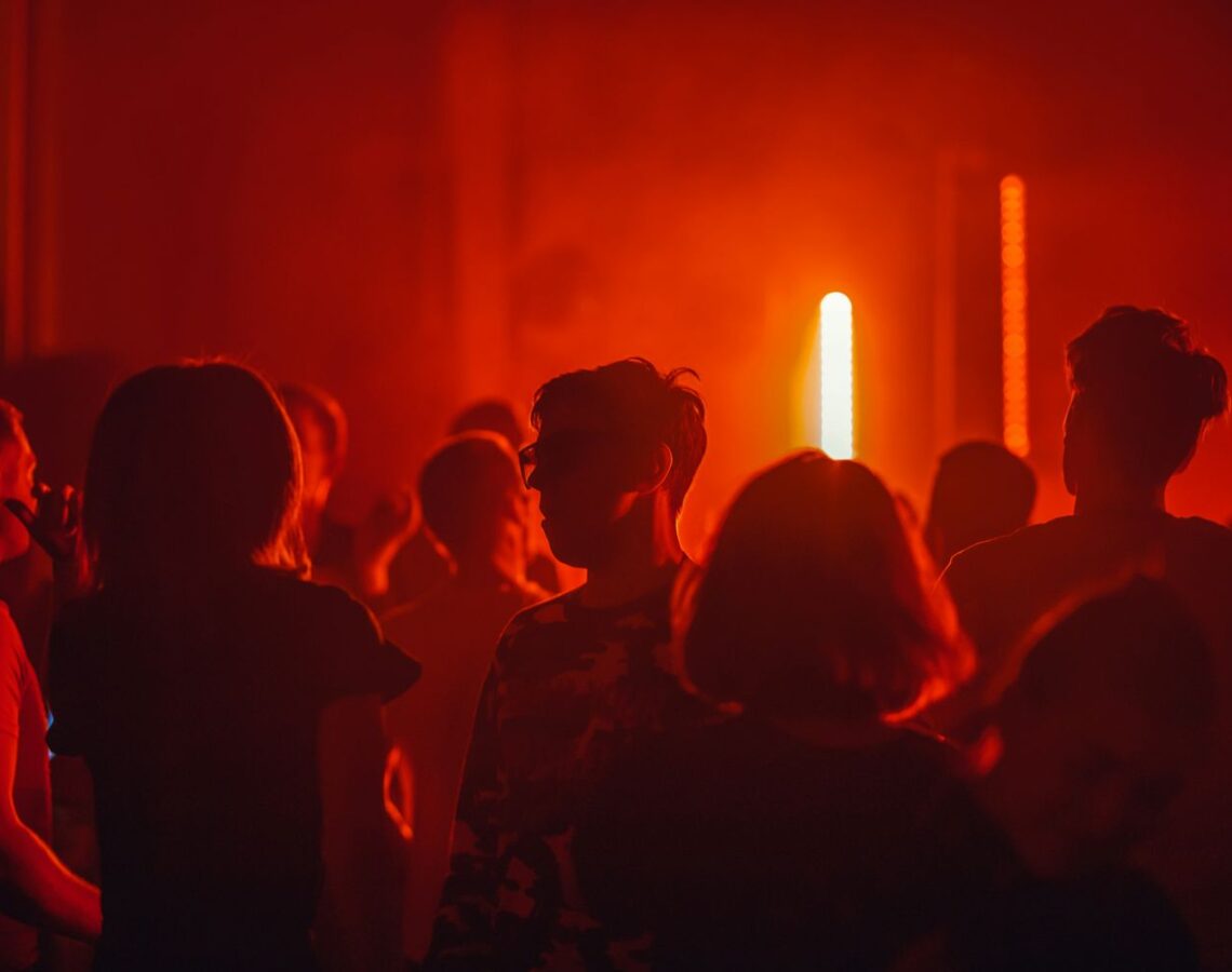 max-titov-9U8dZz8niS0-unsplash tanzende Menschen in rotem Licht