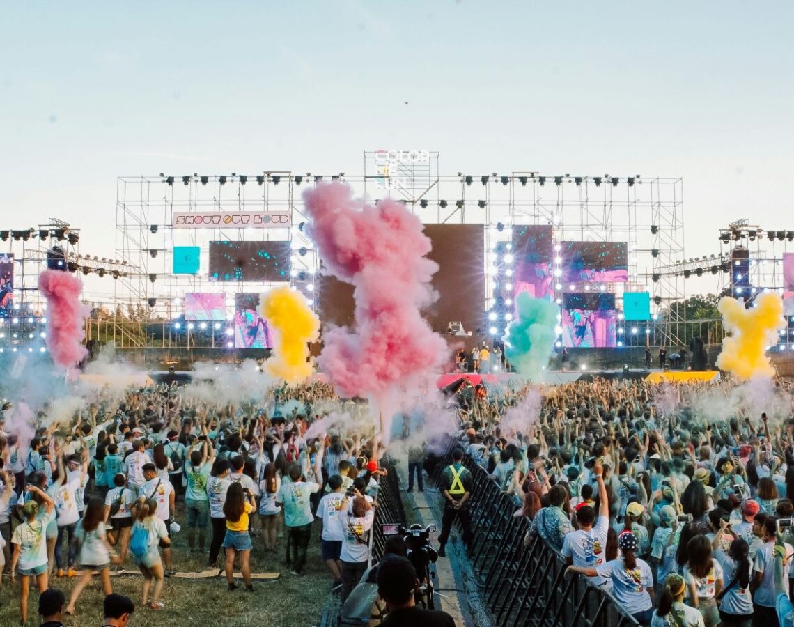 Musikfestival mit Menschenmassen vor Bühne und bunten Fontänen