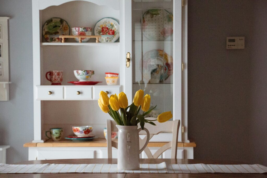Gelbe Tulpen und Schrank mit Teetassen im Hintergrund