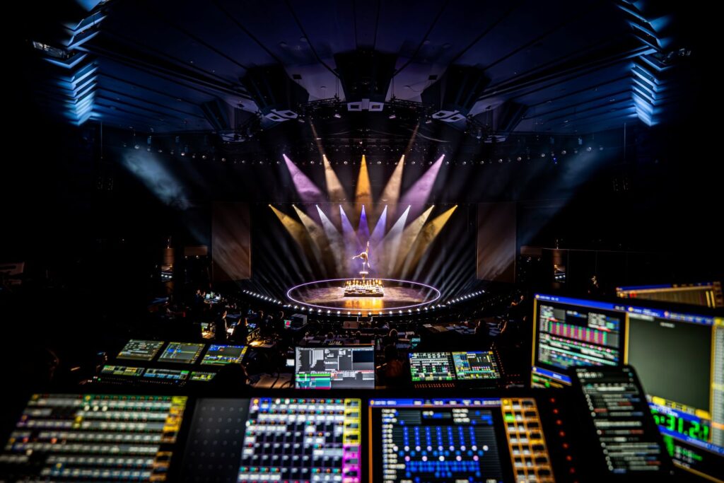Handstand-Akrobatin auf Bühne unter bunten Spotlights, Blick aus dem Saal.