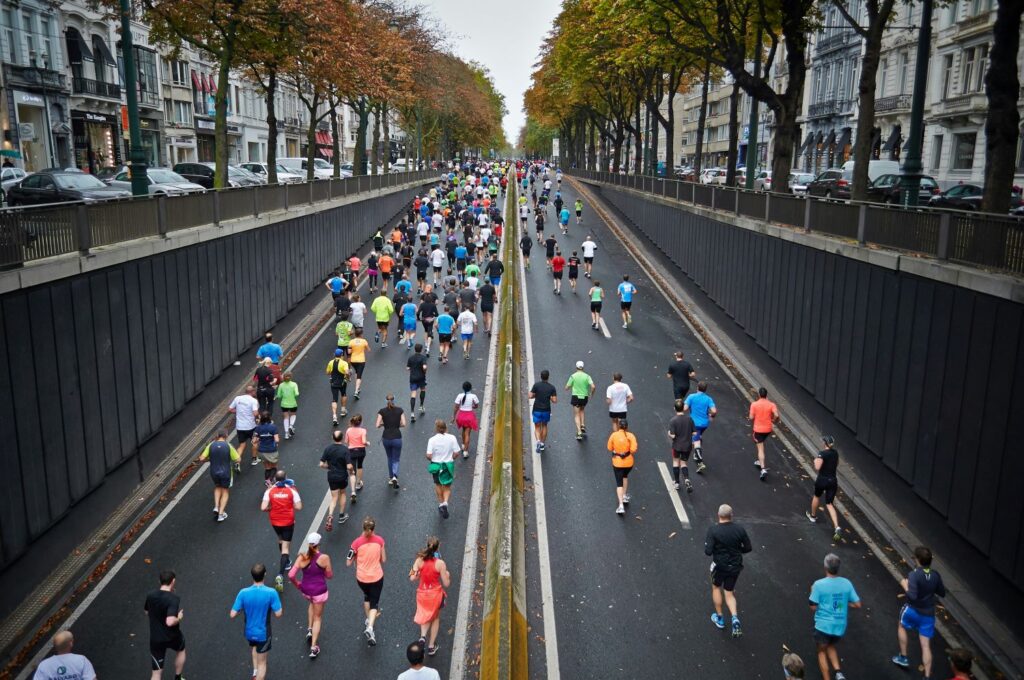 Viele Menschen laufen einen mArathon auf einer zweispurigen Straße