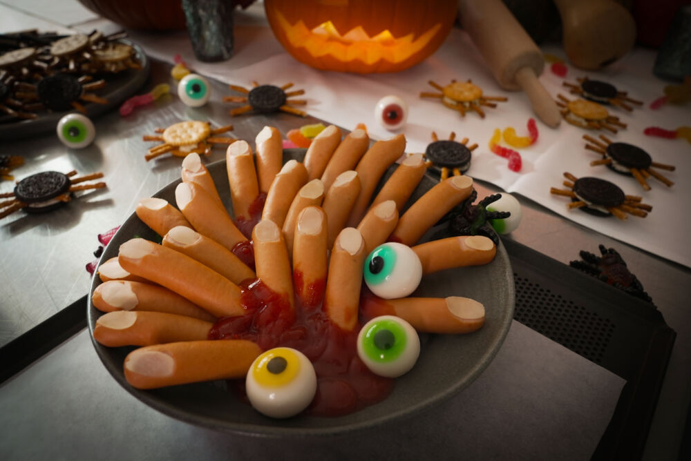 Dekorierter Tisch für Halloweenparty mit Oreokeks Spinnen und Würstchenfingern als Halloween Snacks